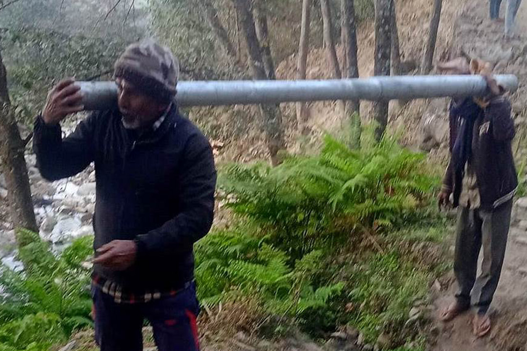 बैतडीको बाइम गाउँमा विद्युतीकरणका लागि पोल बोक्दै स्थानीय